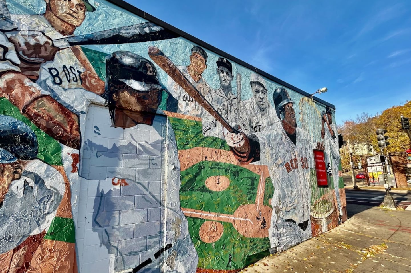 A mural in Roslindale titled “Reversed the Curse” depicts Manny Ramirez, David Ortiz, and Pedro Martinez with other Red Sox players in the background.