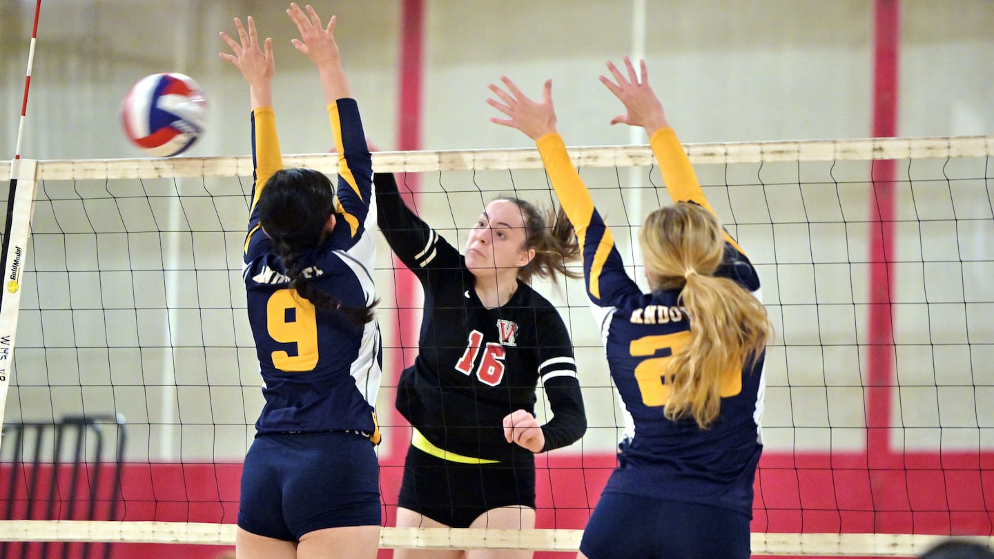 Winchester's Hazel Lovins (16) hammers home a spike between Andover's Jessie Wang (9) and Leah Satlow (21) in Friday's Division 1 first-round win.