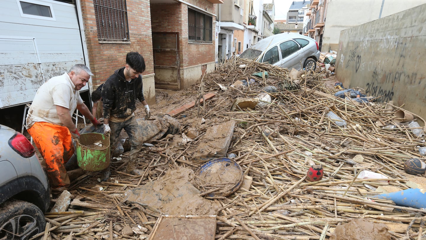 Two men carry a bucket of mud after floods in Paiporta, near Valencia, Spain, on Nov. 3.