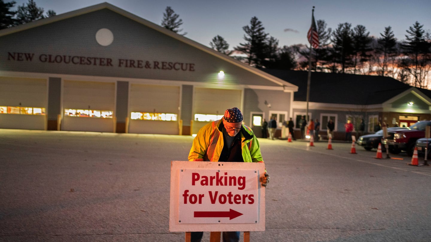 A man set up a sign shortly before the doors opened to voters at a polling location in the fire station in New Gloucester, Maine, in November 2022.