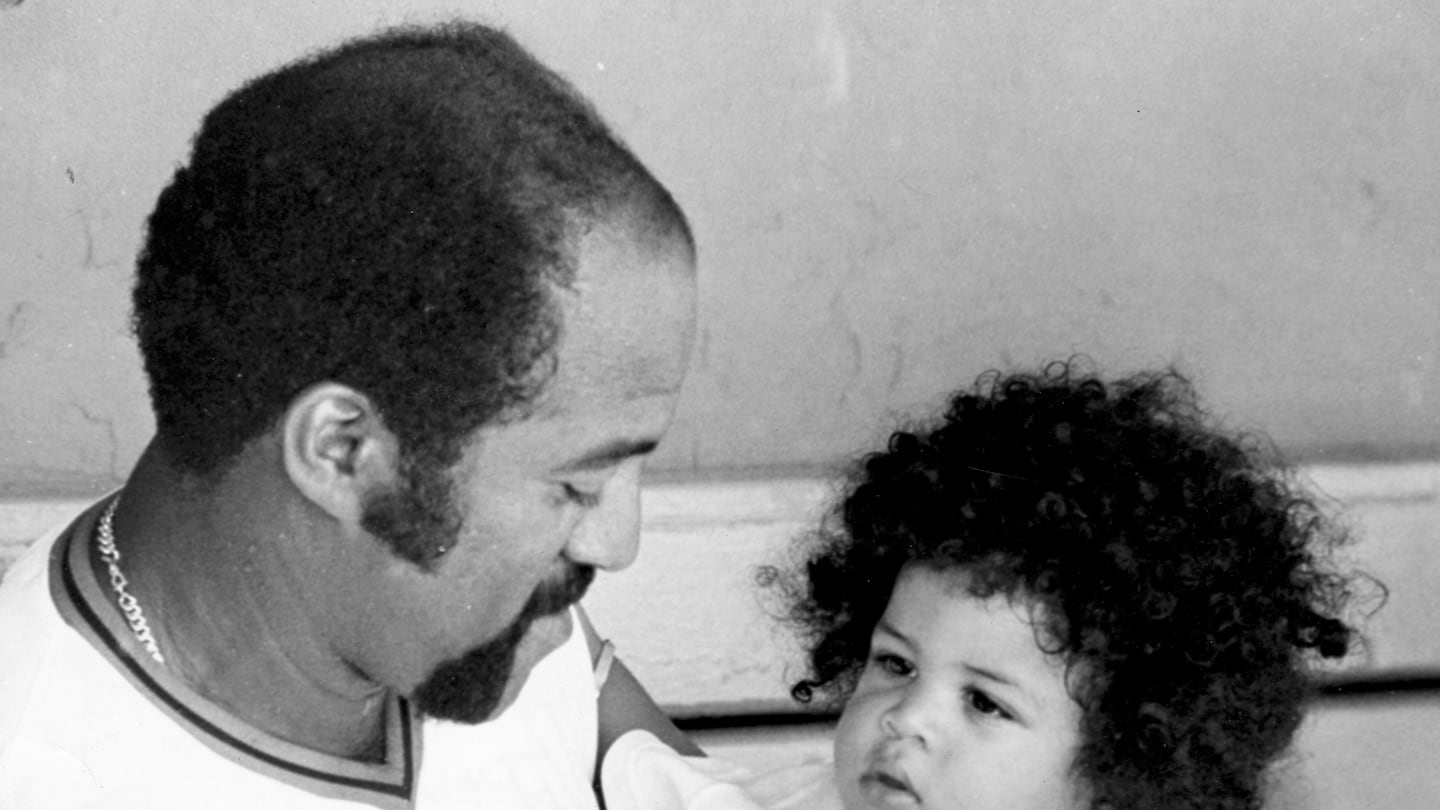 Luis Tiant holds his son, Dan, in the Red Sox dugout in 1975.