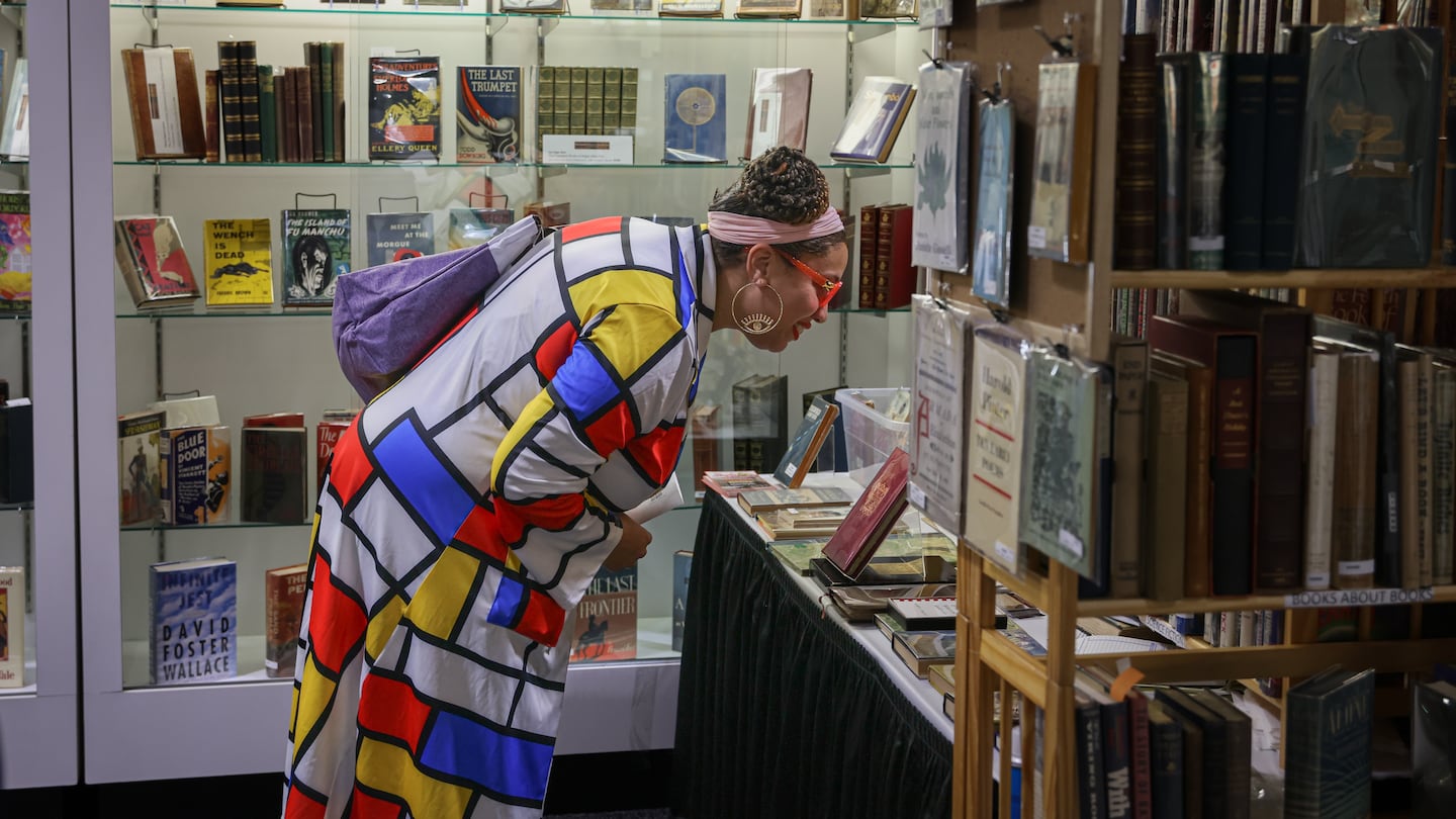 An attendee investigates an antique book at the 2023 Boston International Antiquarian Book Fair.