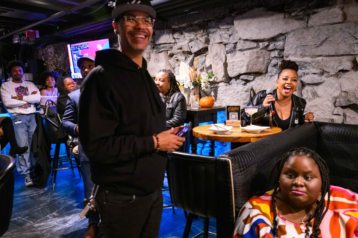 Armenta Pierre (right, holding microphone) explained her vote on a ballot question at an election night watch party at Estella in Downtown Boston Nov. 5, hosted by Boston While Black. James “Jimmy” Hills, host of talk show "Java with Jimmy," stands at left.