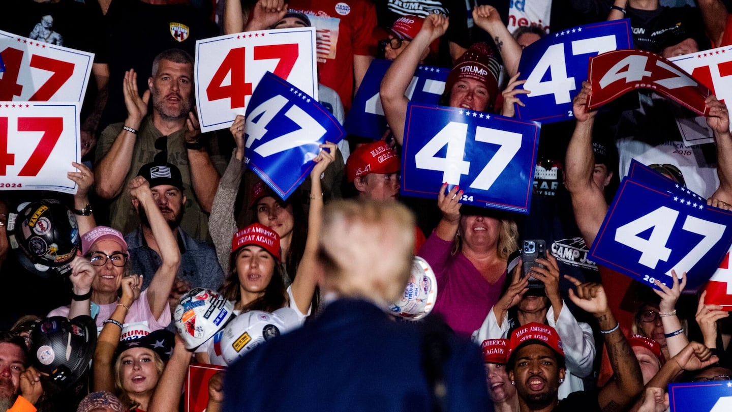 Attendees hold up "47" signs as former US President Donald Trump, center, watches during a campaign event in Greensboro, North Carolina, US, on Tuesday, Oct. 22, 2024.