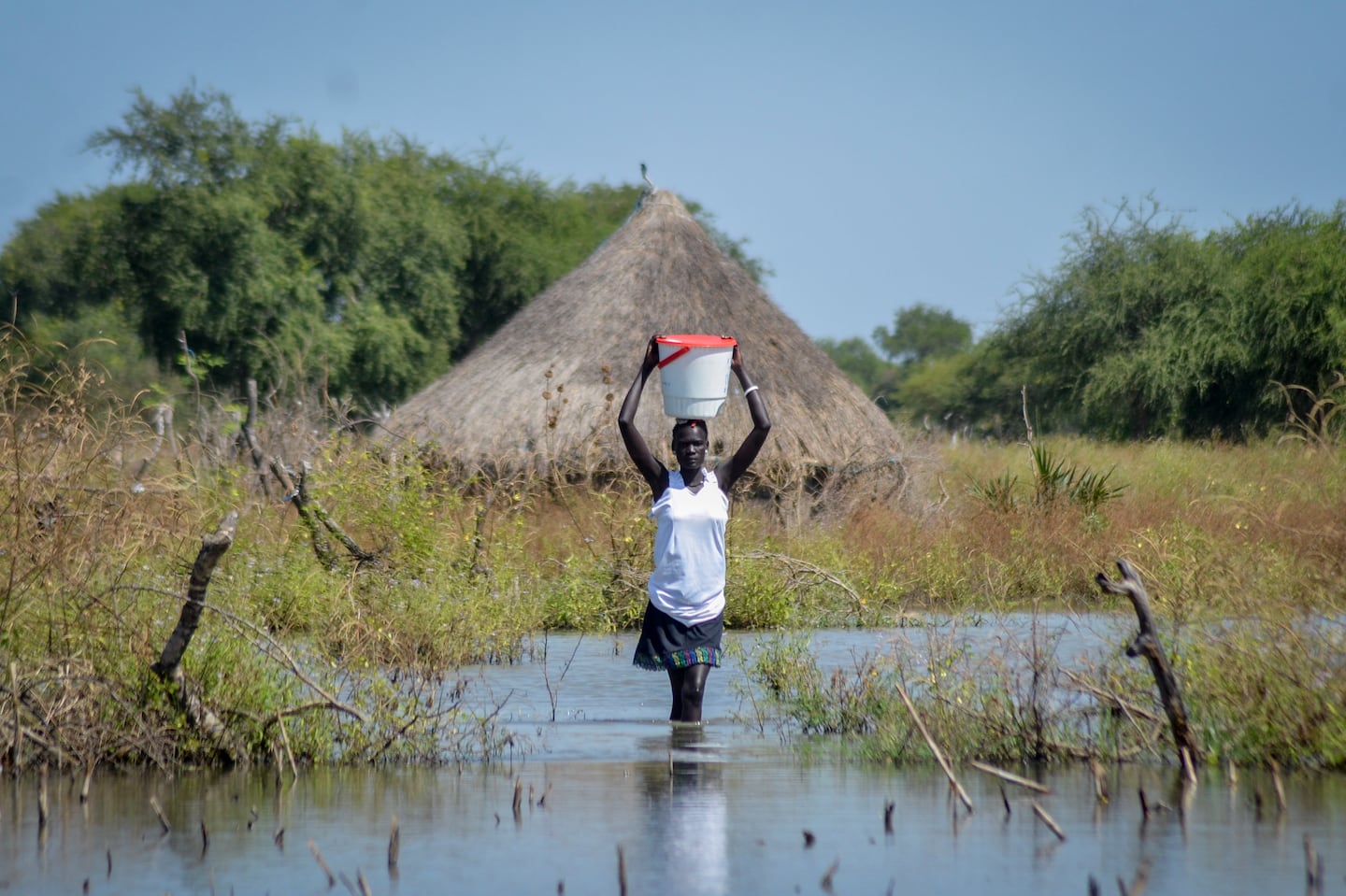 A woman carries a bucket on her head as she wades through floodwaters in the village of Wang Chot, in South Sudan, on Nov. 26, 2020.