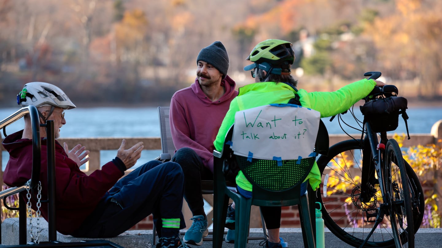 Eben Kunz, left, and Gail Boettiger, right, take a break from their bike ride to talk with Ben (who asked to be identified by his first name only), near the boathouse on Jamaica Pond. Following the election Ben and his friend Alexander Kelly decided to set up shop for impromptu therapy, or what Ben referred to as, public listening.