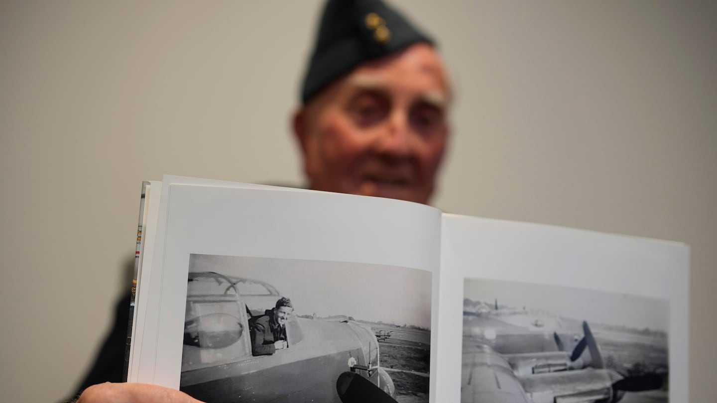 Michael Woods, a 100-year-old World War II veteran, showed a photo of himself during an interview in Dunstable, Bedfordshire, England, on Tuesday.