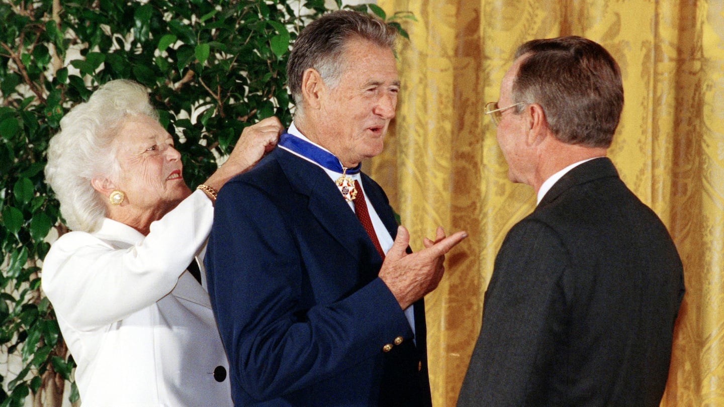 President George W. Bush (right) presents the Presidential Medal of Freedom to baseball great Ted Williams as Barbara Bush ties the medal around his neck on Nov. 18, 1991, at a White House ceremony in Washington. That medal, along with other memorabilia, will be put up for auction by the estate of his daughter Claudia, who died last December.