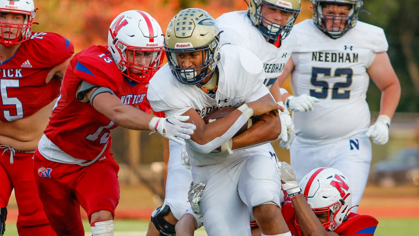 Tackling Needham High senior Aidan Williams (5) requires an all-out effort, exhibited by Natick's John Carroll (13) and Erick Ferro (4).