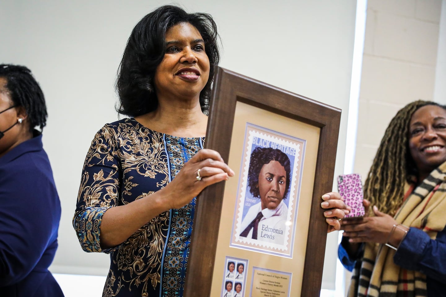 Author Lisa Braxton-Reid, left, in 2022. when serving as president of the National Council Negro Women - Greater Boston Chapter,  is gifted a framed print of a stamp honoring Edmonia Lewis. On Friday, Braxton-Reid will discuss her book “Dancing Between the Raindrops: A Daughter’s Reflections on Love and Loss,” at a caregiving workshop in Roxbury.