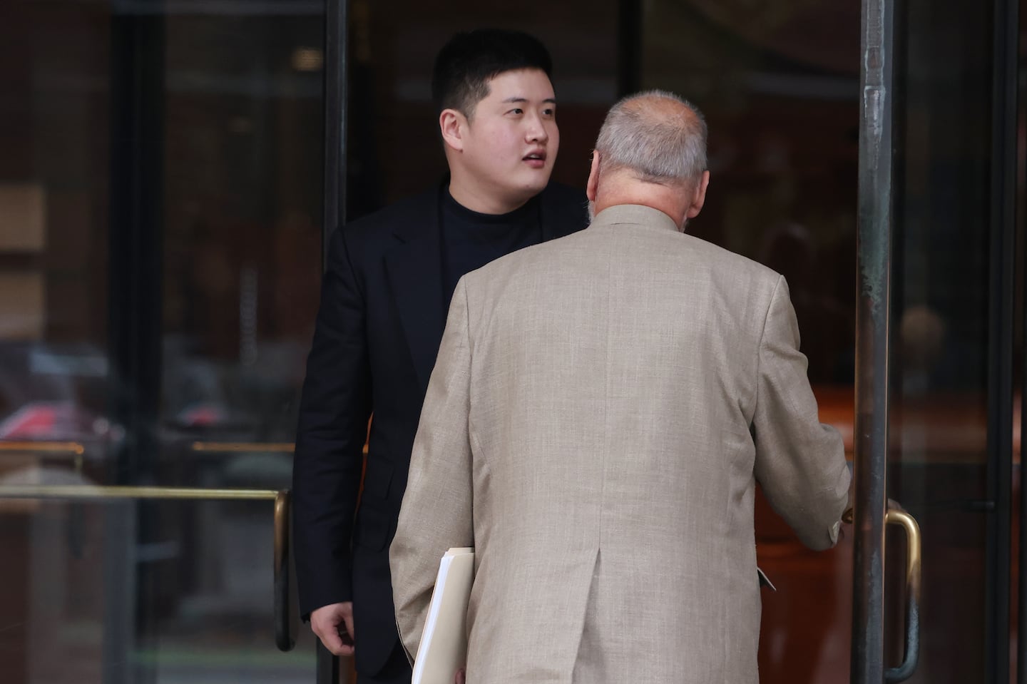 Junmyung Lee, left, accused of being one of the people operating the brothel network in Cambridge and Watertown, exited the John Joseph Moakley Federal Courthouse with his lawyer, John Amabile, after pleading guilty on Oct. 30.