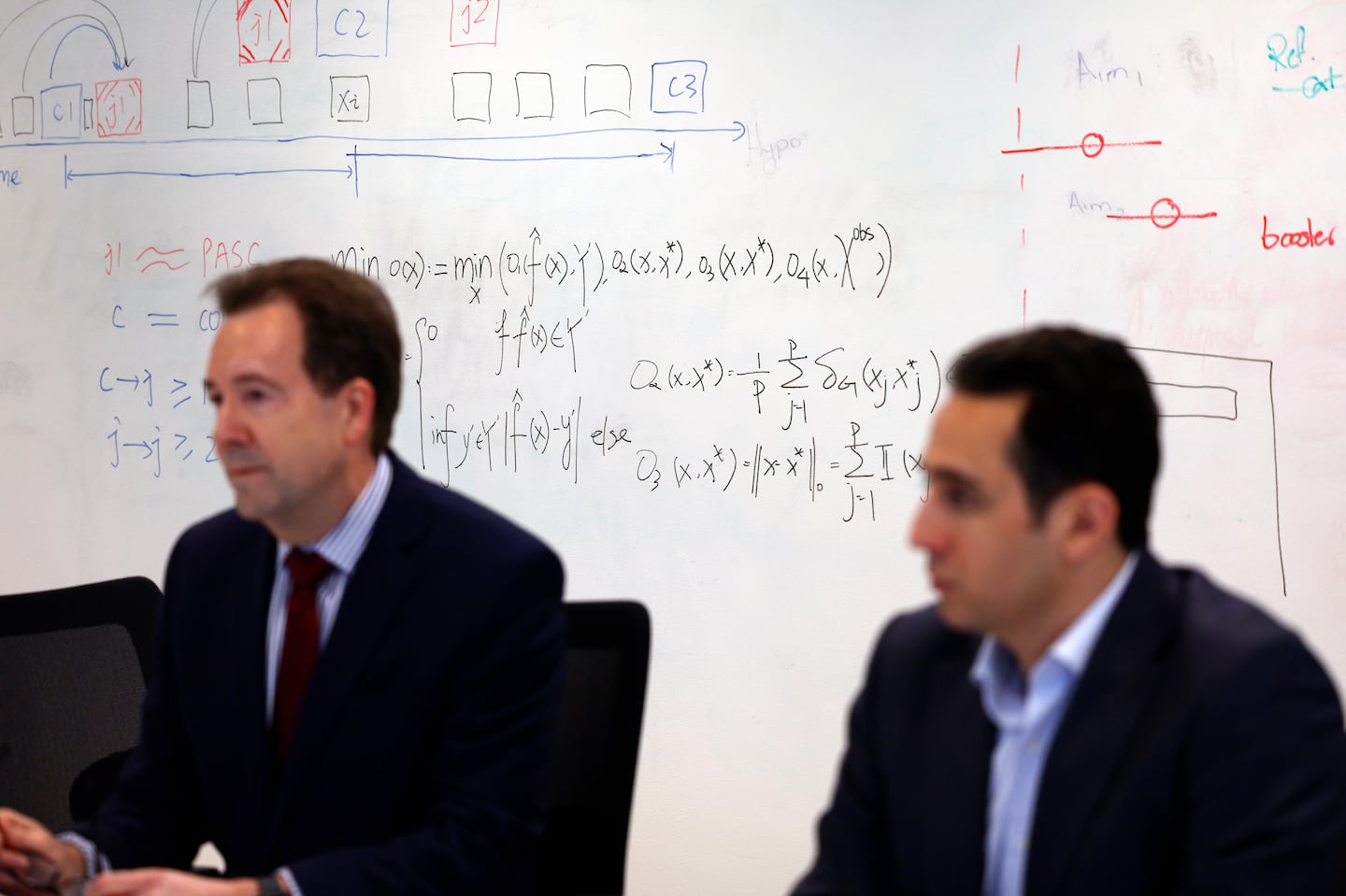 Part of the algorithm that can diagnose long COVID by scanning medical records can be seen behind Shawn Murphy (left), chief research information officer at Mass General Brigham and co-director of its Center for AI and Biomedical Informatics, and Hossein Estiri, head of AI Research at CAIBILS, co-authors the algorithm.