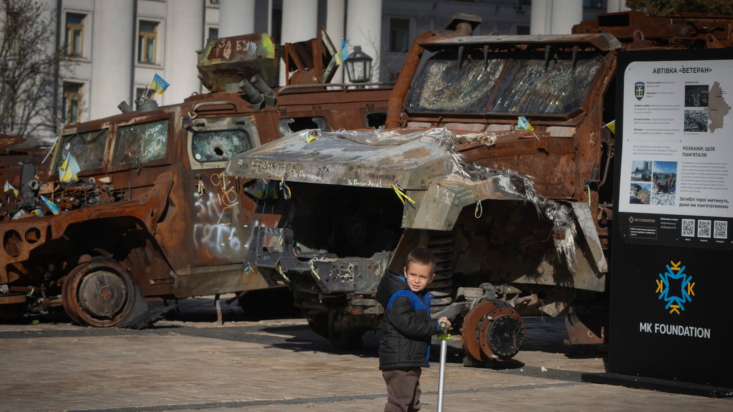 A boy rides a scooter past a display of destroyed Russian military vehicles in Mykhailivska square in central Kyiv, Ukraine.