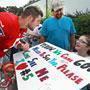 After asking her name, Tim Tebow autographs the poster of wheelchair-bound Madelin Beardsley of Virginia Beach, as her father Scott looks on.