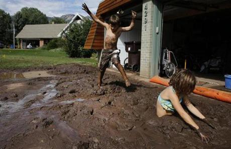  Noe Sura, 7, right, and her brother Eli, 7, played in the mud-clogged ground around their home after days of flooding, on the southern edge of Boulder, Colo., Saturday.
