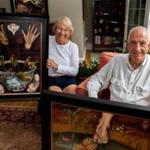 Sydney Lewis Glover and her husband, J. Denis, with a few of her mother’s Surrealist  paintings. Glover found them after Doris Lindo Lewis died in 1995.