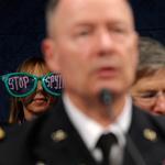Protesters sat behind General Keith Alexander as he testified Tuesday about the NSA’s intelligence-gathering practices.