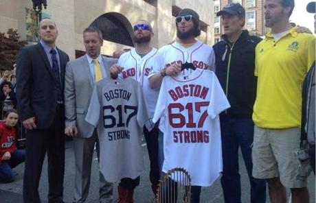 Red Sox players held jerseys as they stood in front of the World Series trophy at the Boston Marathon finish line. 
