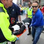 Celeste Corcoran of Lowell is carried in a stretcher over the finish line of the Boston Marathon as her husband Kevin, right, follows. Celeste lost both her legs. 