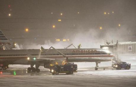 Workers at Logan airport de-iced a plane.
