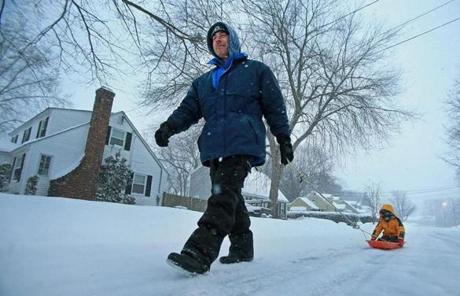 John Stanisewski pulled his 8-year-old son, Jack, through the snow on Jefferson Street in Lawrence.
