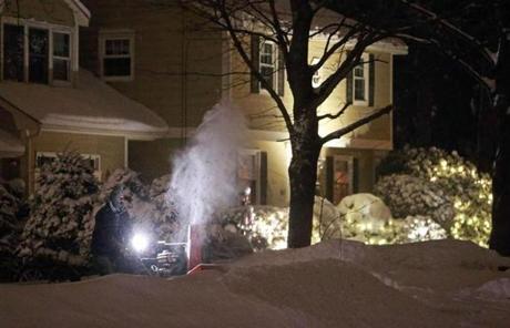 A driveway in North Andover was cleared by snow blower, with a neighbor's Christmas lights helping out the light on the machine.
