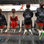 Sweepers, who clean the ice of flowers, stuffed animals, and other tossed objects, lined up to watch the competitors in the 2014 Prudential US Figure Skating Championship on a temporary rink at the Convention Center in South Boston.