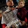 Jon Lester holds two valuable properties — the World Series trophy and his son Hudson — after the Red Sox clinched the title last fall.. (Photo by Jamie Squire/Getty Images)