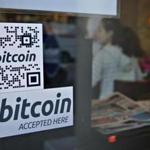 Signs on a window advertise a bitcoin ATM machine.