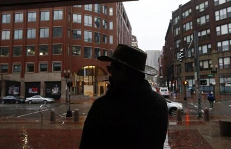 A man is silhouetted as he stepped outside of South Station to smoke a cigarette on Nov. 27, 2013.
