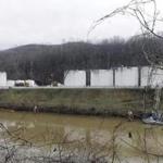 Workers inspected an area outside a retaining wall around storage tanks where a chemical had leaked into the Elk River.