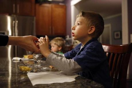 Thomas Estey was handed a hamburger on a gluten-free bun by his mother, Lora, at their West Roxbury home.
