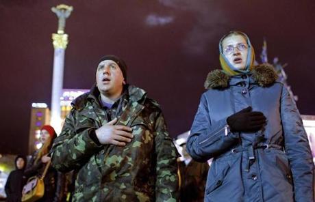 A Ukrainian couple held their hands over their hearts while singing the Ukrainian national anthem in Independence Square in Kiev, Ukraine. 
