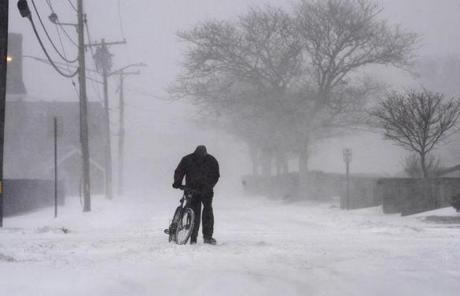  A cyclist walked with his bicycle in white out conditions in Hyannis.
