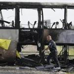 A California Highway Patrol officer walked around the remnants of a tour bus that exploded after it was struck by a FedEx truck. Ten people were killed and dozens injured.