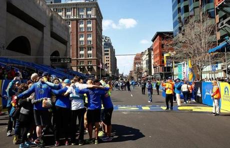 A group huddled together after crossing the Boston Marathon finish line during the Tribute Run.
