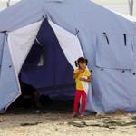 An Iraqi refugee stands outside her family's tent at Khazir refugee camp outside Irbil on Wednesday.