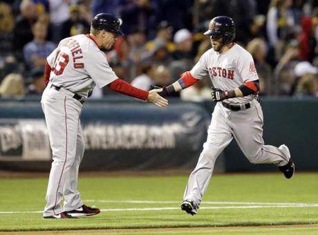Dustin Pedroia, right, is congratulated by third base coach Brian Butterfield after hitting a two-run home run off Oakland Athletics' Scott Kazmir in the sixth inning.
