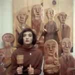 Marisol poses in 1958 in New York with her tools and some of her wooden sculptures.
