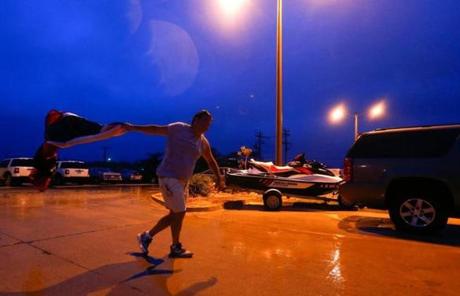 Carter Cromley carried the cover for his jet ski that was blown off while Arthur ravaged Nags Head, N.C., early Friday.

