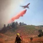 An aircraft dropped fire retardant on a vineyard as firefighters battled a wildfire near Plymouth, Calif., Saturday. 