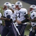 New England Patriots tight end Rob Gronkowski, center, warms up on the field with teammates during an NFL football training camp practice at Gillette Stadium, Sunday, July 27, 2014, in Foxborough, Mass. (AP Photo/Steven Senne)