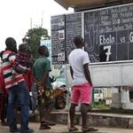 Liberians read a chalkboard on the Ebola outbreak in Monrovia on Saturday. Guinea closed its borders with Sierra Leone and Liberia to try to curb the virus. 