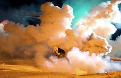 A protester took shelter from smoke billowing around him Wednesday night. 
