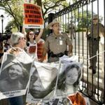 Pro-abortion rights activists chanted slogans on Monday while a Texas Department of Public Safety trooper removed their signs from the gate of the Governor's Mansion in Austin.