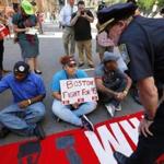 A Boston police officer warned fast-food workers sitting in an intersection that they would be arrested if they did not move.