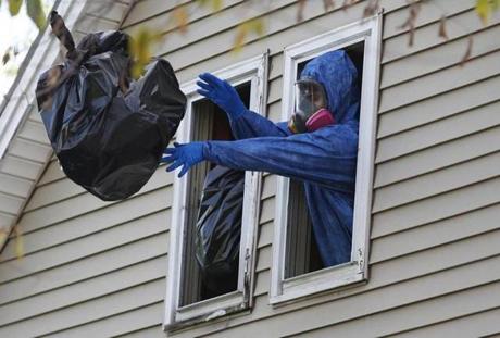 Workers in hazmat suits remove bags of waste from Erika Murray's home in Blackstone.  
