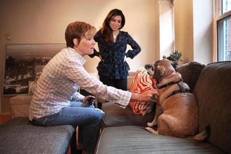Elizabeth Swartz (left) of Westwood prepares to leave her puggle, Fenway, with pet sitter Rachel Askew in her North End apartment. 

