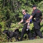 Detective Matt Denis of the Vermont State Police, left, and Trooper Charles Bergeron of the Rhode Island State Police and the search dog Zeus were in the woods near the Higgins Pool in Lawrence.