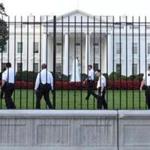 Uniformed Secret Service officers walk along the fence on the North side of the White House